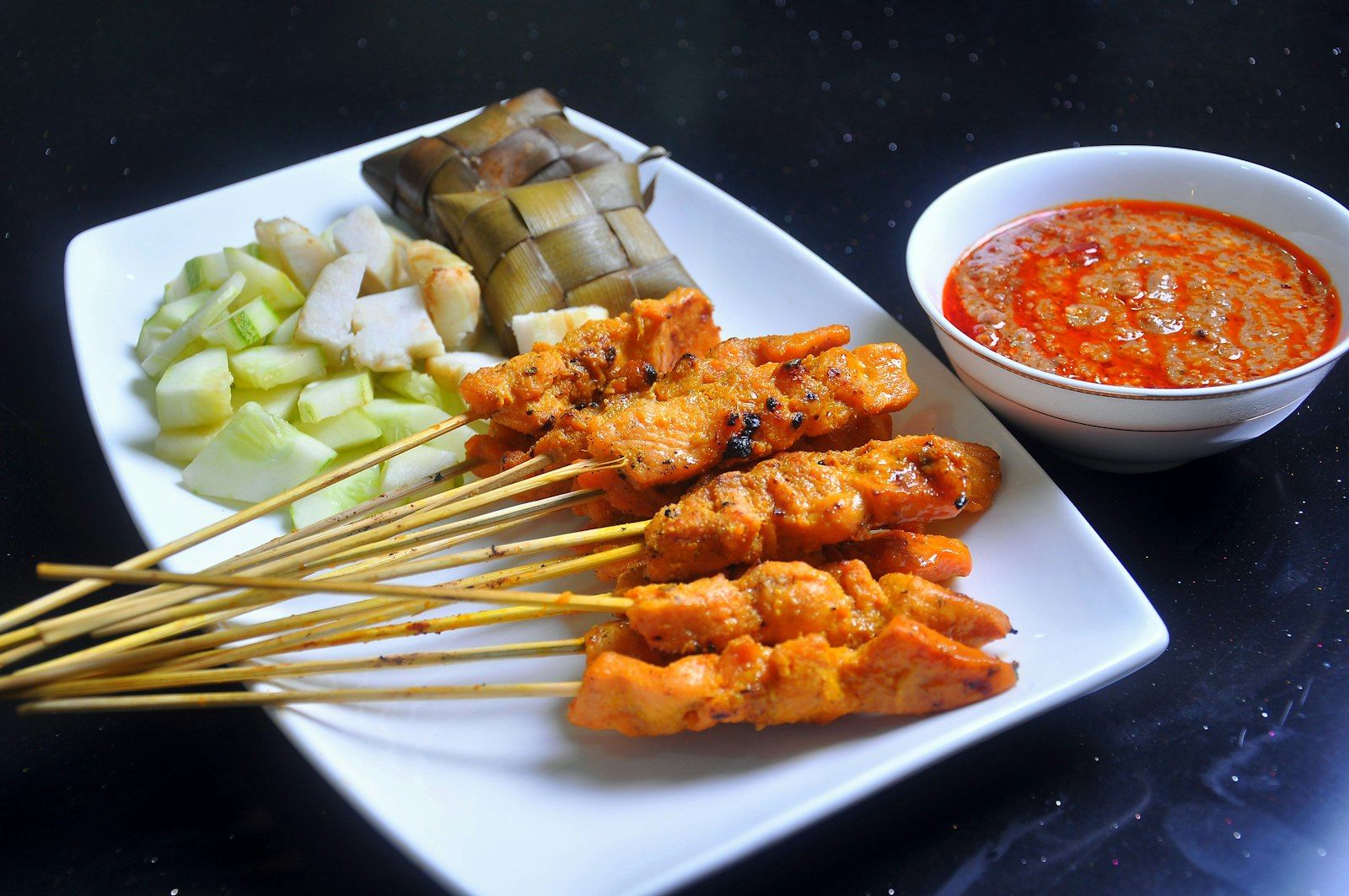 Grilled chicken satay skewers served with a small bowl of peanut dipping sauce