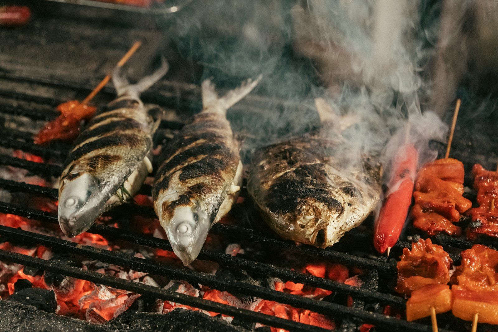 Fresh fish grilling over coals at a Phuket street food stall