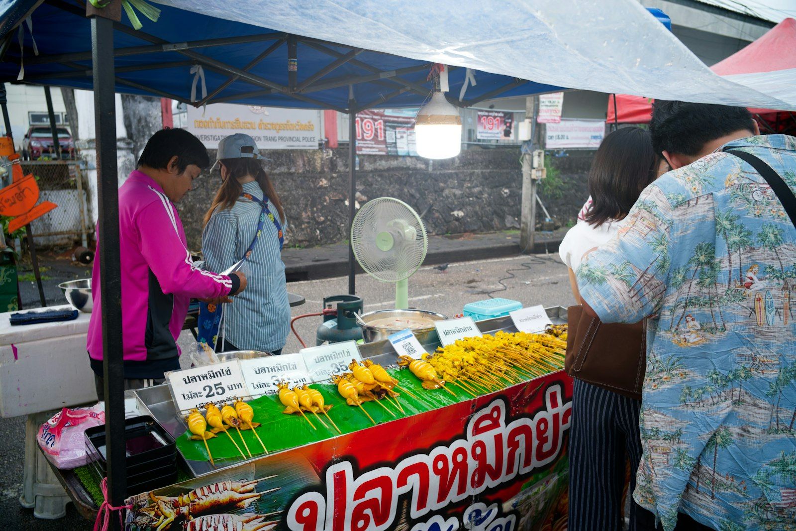A Thai street food stall lined with grilled skewers at a night market