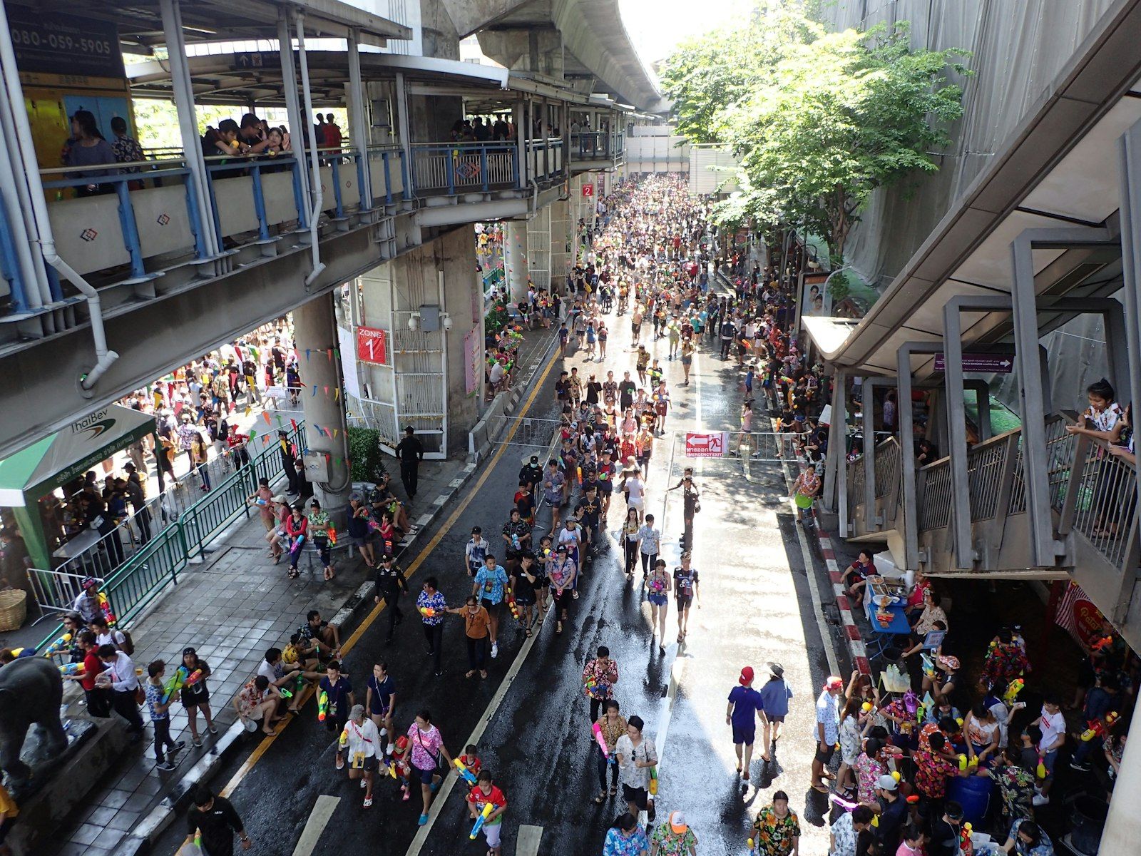 Eine Menge feiert Songkran auf einer durchnässten Stadtstraße