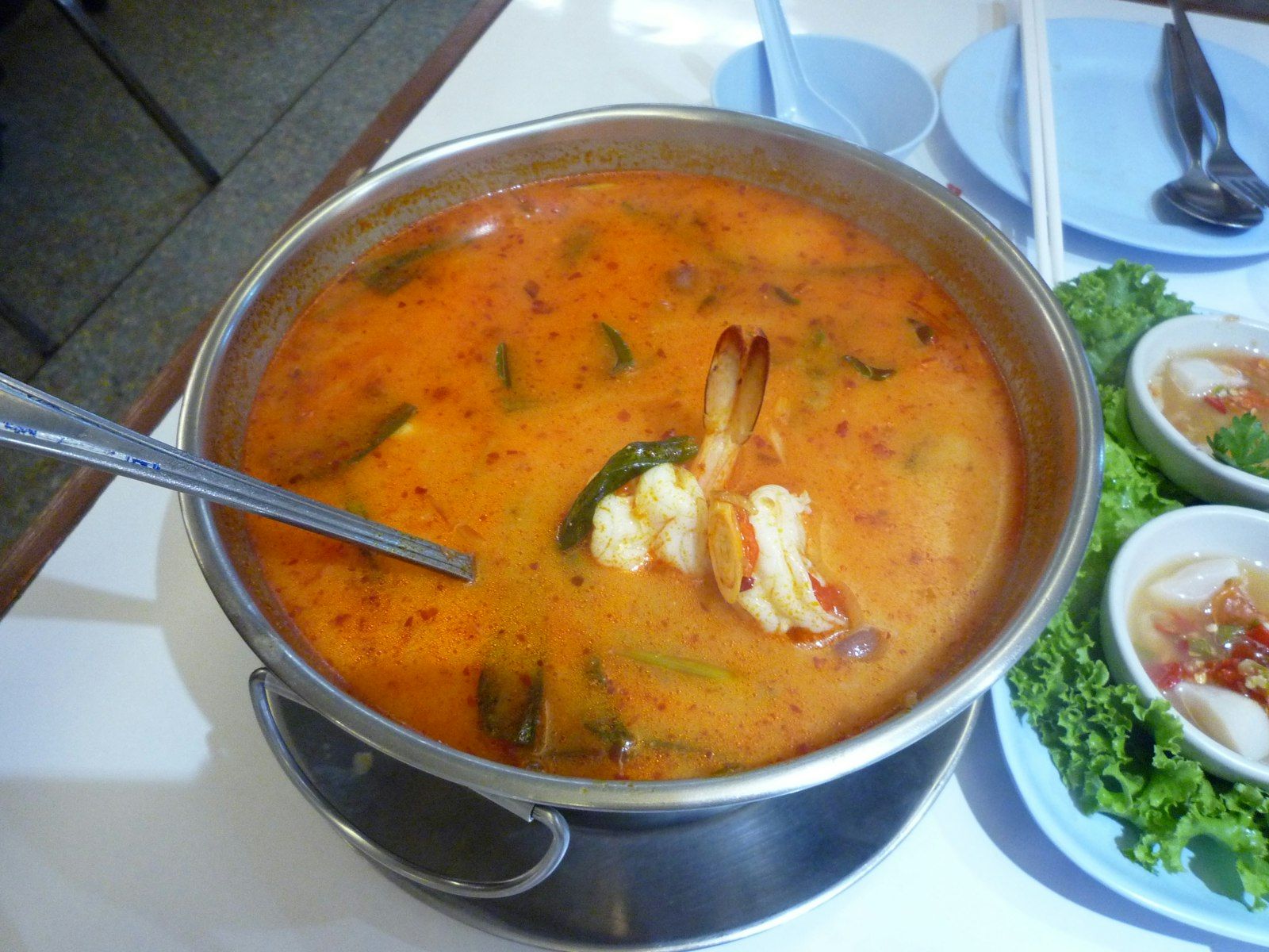 A steaming bowl of clear tom yum goong with prawns and fresh herbs