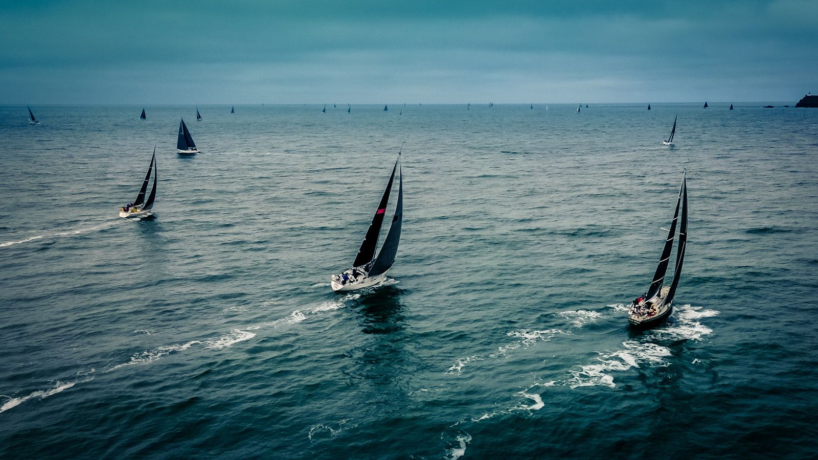 Yachts racing offshore under full sail, evoking the PYC Yachting Festival in Phuket