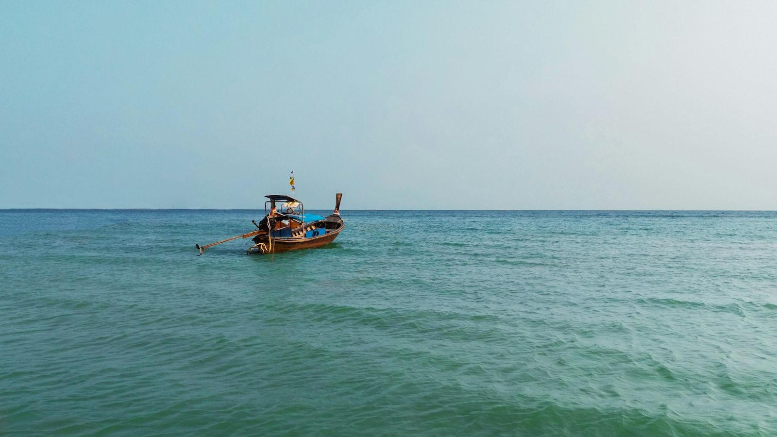 Boat approaching a floating beach club on open turquoise water near Phuket