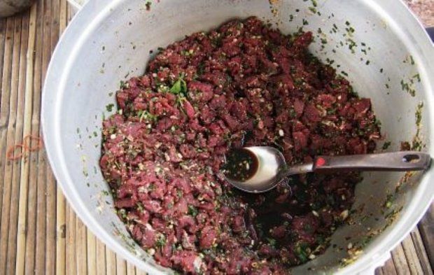 A metal bowl of Thai larb leuat, finely chopped raw beef with blood and herbs