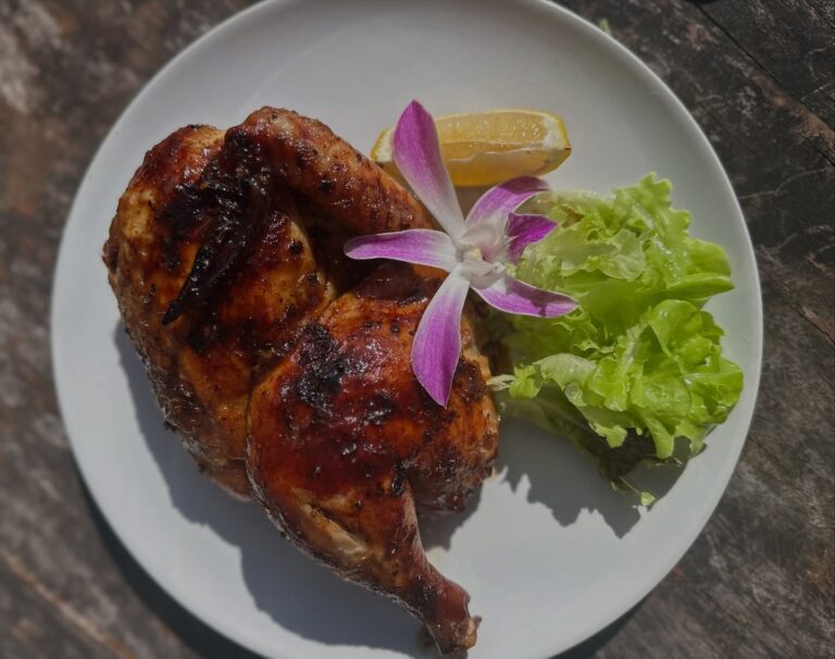 Grilled half chicken with lemon, lettuce and orchid garnish at Denz Cafe, a Thai and Western cafe in Patong, Phuket