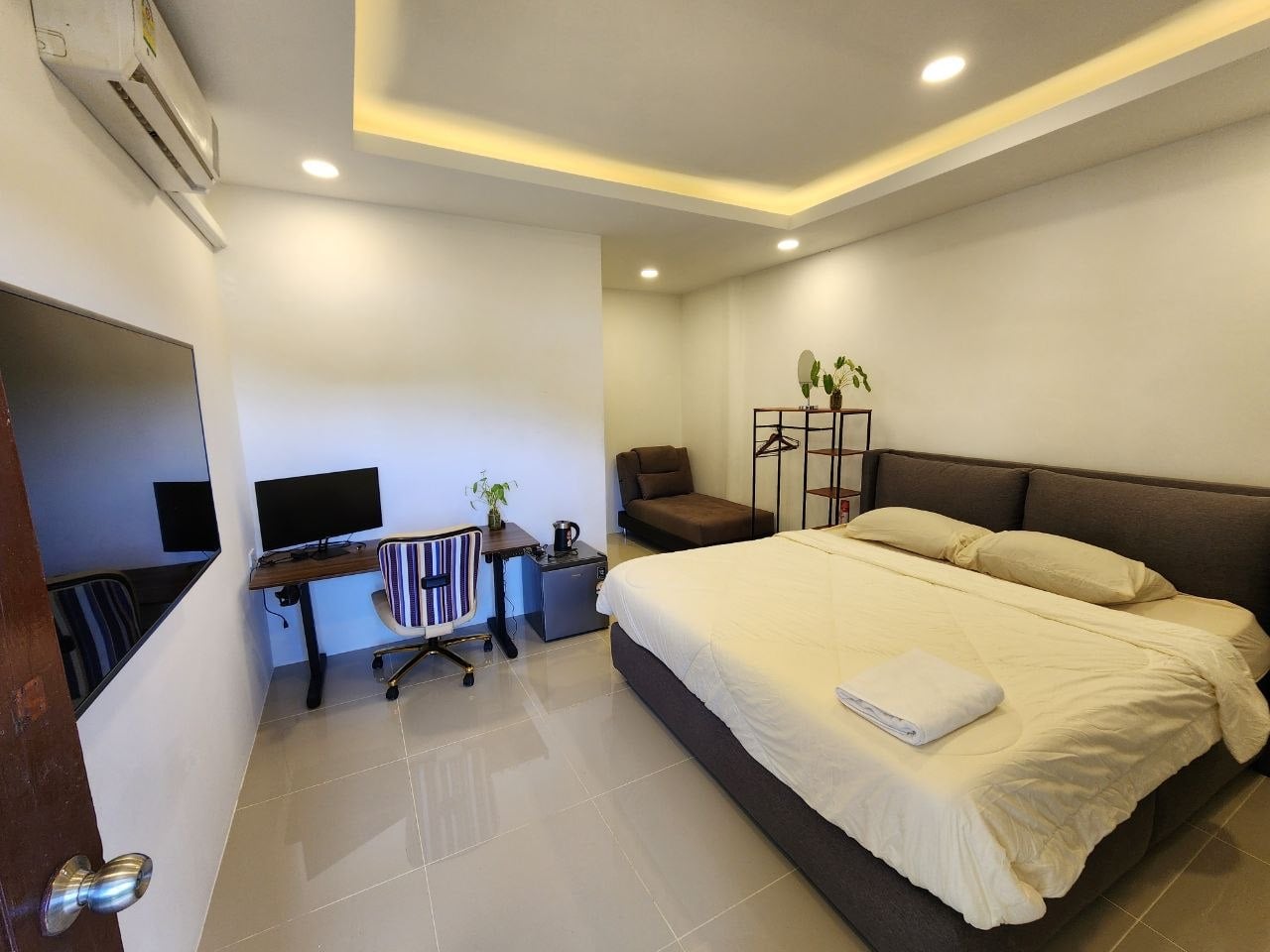 Bright studio room with king bed, work desk, monitor, ergonomic chair and mini fridge at Denz WorkStay, Patong Phuket