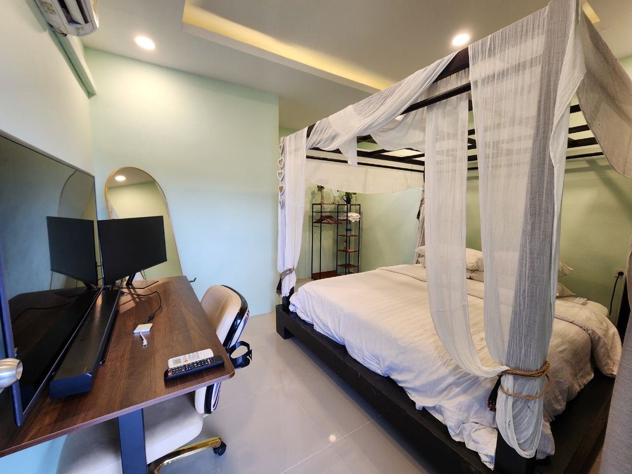 Guesthouse room with four-poster canopy bed, desk with dual monitors and ergonomic chair at Denz WorkStay, Patong Phuket