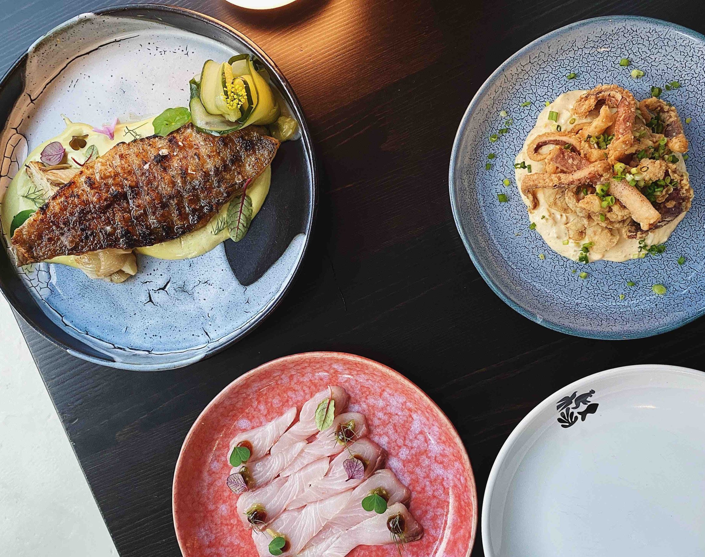 Overhead trio of dishes at Heh contemporary restaurant, grilled fish, fried squid and kingfish crudo, Old Town Phuket