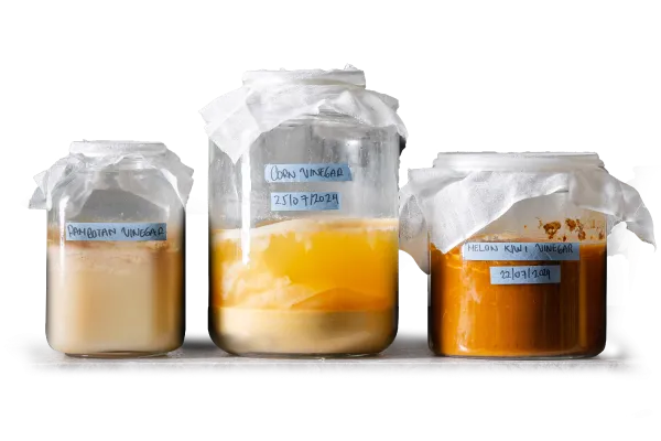 Three labelled jars of house-fermented rambutan, corn and melon kiwi vinegar at hom modern cuisine restaurant in Kamala, Phuket