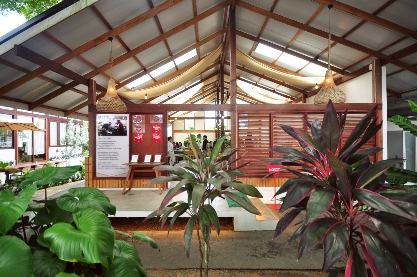 Pitched wooden roof, woven pendant lamps and tropical plants in the open-air dining area at Kin-Kub-Ei, Bang Tao, Phuket