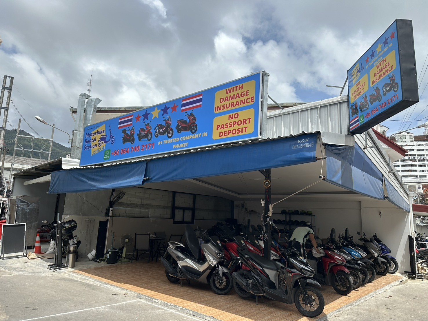 Blue signage storefront with rows of parked scooters under an awning at Motorbike Rental Station Phuket, Patong