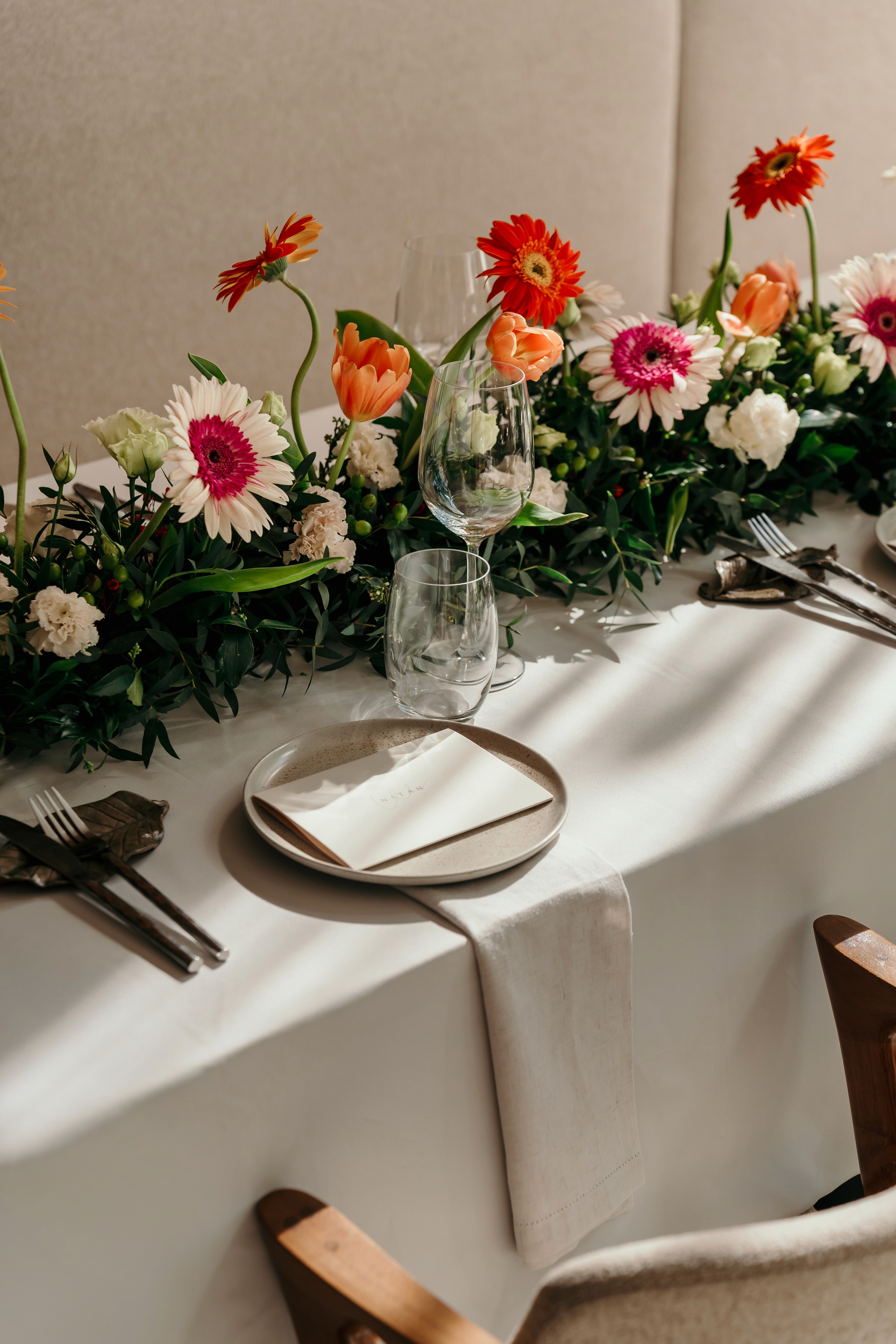 Elegant table set with gerbera and tulip centerpiece, wine glasses and place setting at Nitan Southern Thai restaurant, Bang Tao, Phuket