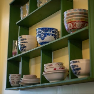 Green wall shelf of antique blue-and-white and floral Chinese porcelain bowls inside One Chun Southern Thai restaurant, Phuket Old Town