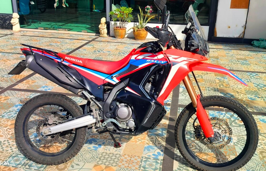 Side profile of a red Honda CRF Rally dual-sport with knobbly off-road tyres at Phuket CRF Off-Road & Enduro Rentals in Patong, Phuket.