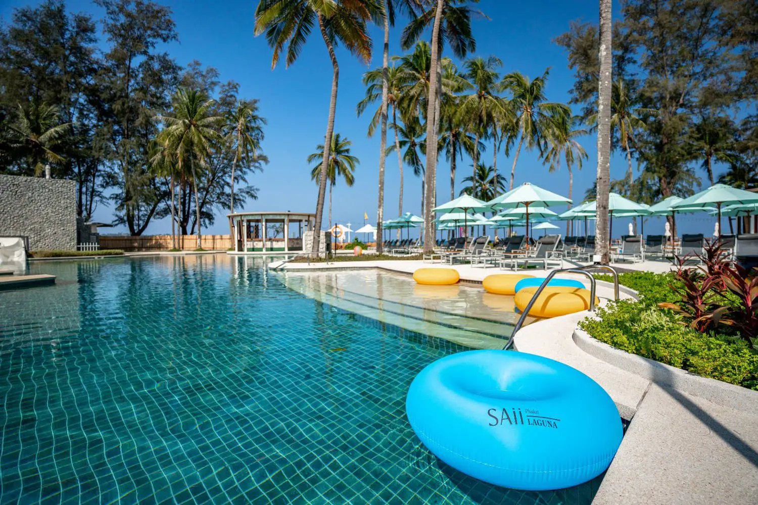 Palm-lined swimming pool and loungers at SAii Laguna Phuket, Bang Tao