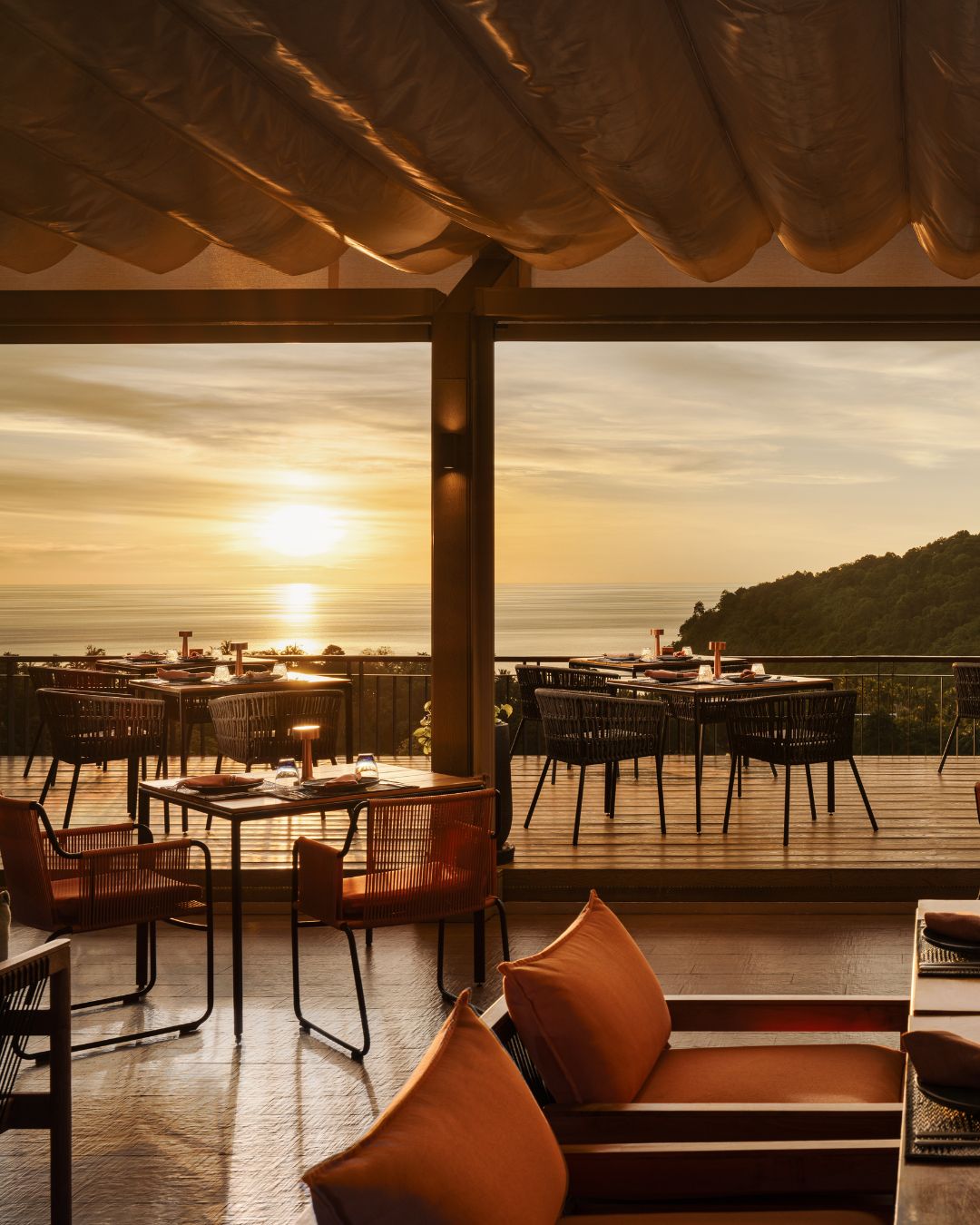 Rooftop dining terrace set for dinner at Sizzle, overlooking the Andaman Sea at sunset in Patong, Phuket.