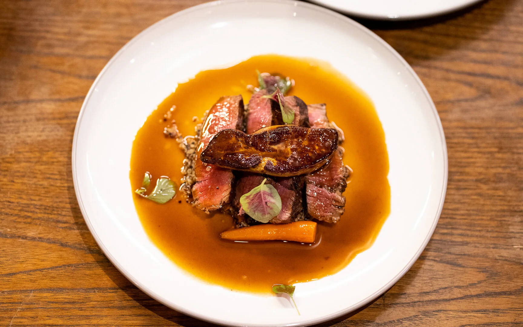 Plated slices of seared beef topped with foie gras and glossy jus at Suay, a Thai contemporary restaurant in Bang Tao, Phuket