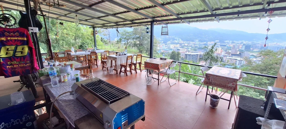 Open-air hillside terrace with a barbecue grill and Patong town view, a rest stop along the JunJaow Trail in Patong, Phuket