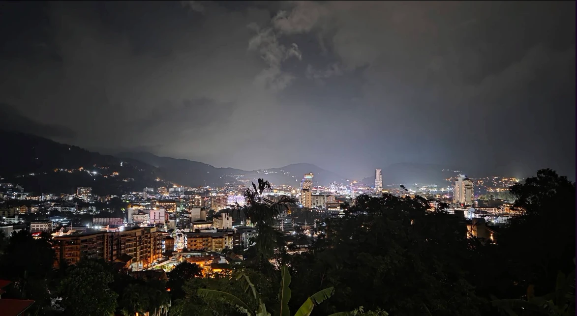 Panoramic night view of Patong's lit skyline and hills seen from Ta Yong Garden Cafe, a Thai hillside cafe in Patong, Phuket