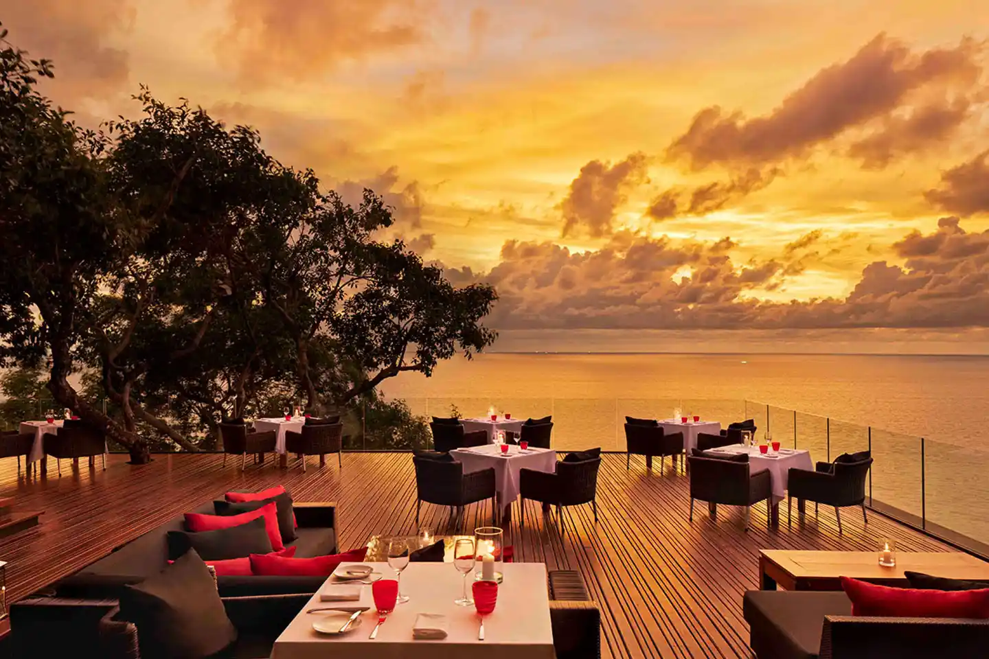 Open-air clifftop dining terrace with white-clothed tables overlooking the Andaman Sea at sunset, Talung Thai restaurant in Kamala, Phuket