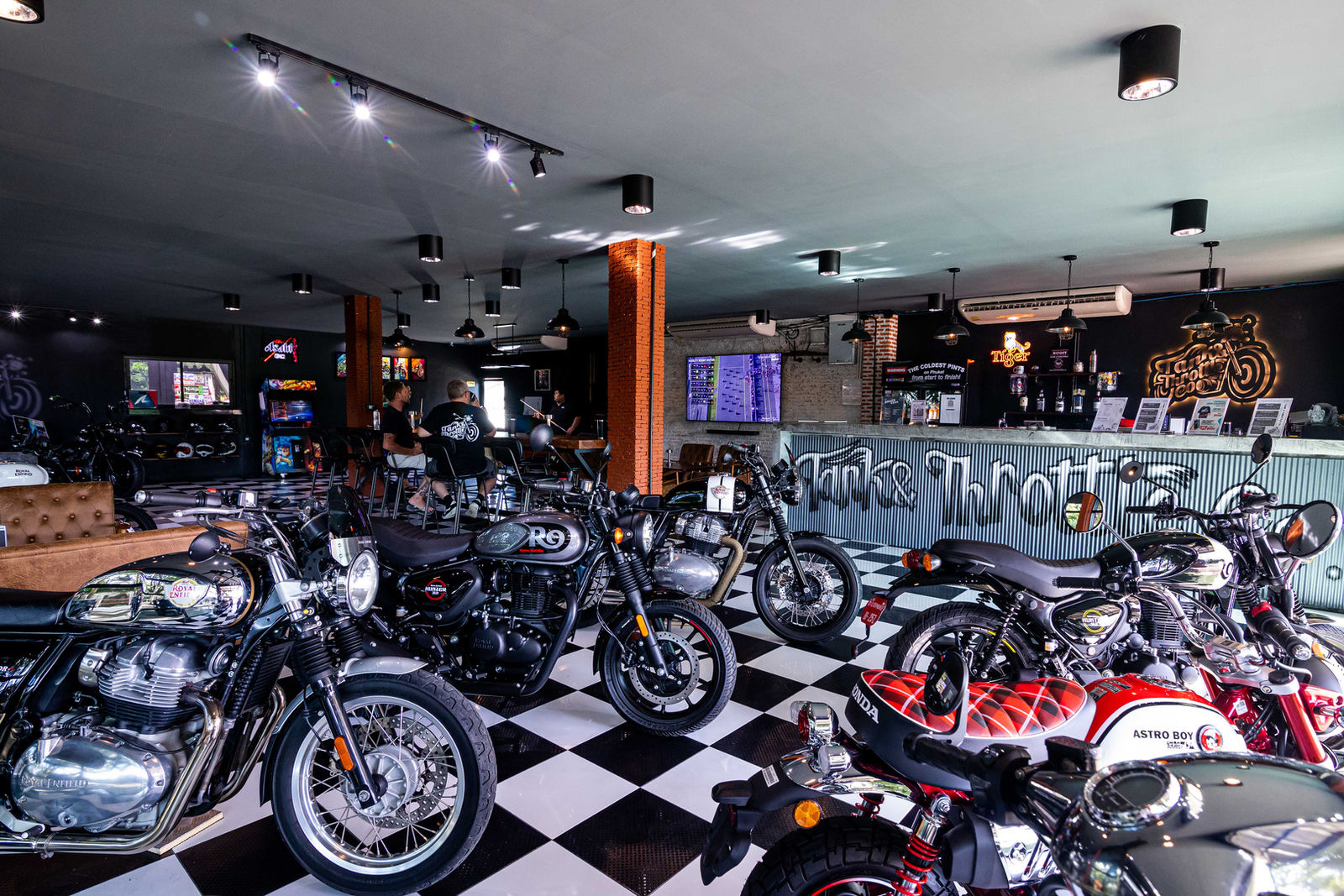The Tank and Throttle Co. clubhouse and bar in Chalong, Phuket, with a row of motorbikes on a checkerboard floor
