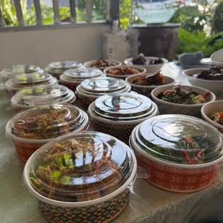 Bowls of Southern Thai dishes in lidded containers on a table at Ton Mayom restaurant in Old Town, Phuket